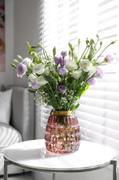 Photo of Bouquet of beautiful Eustoma flowers on table in room
