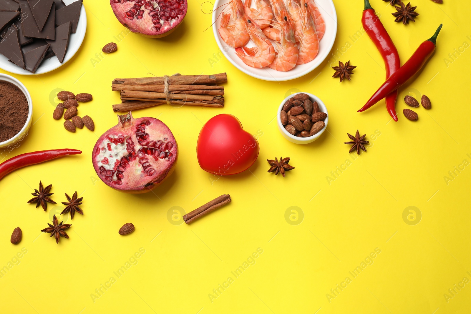 Photo of Natural aphrodisiac. Different products and heart model on yellow background, flat lay. Space for text