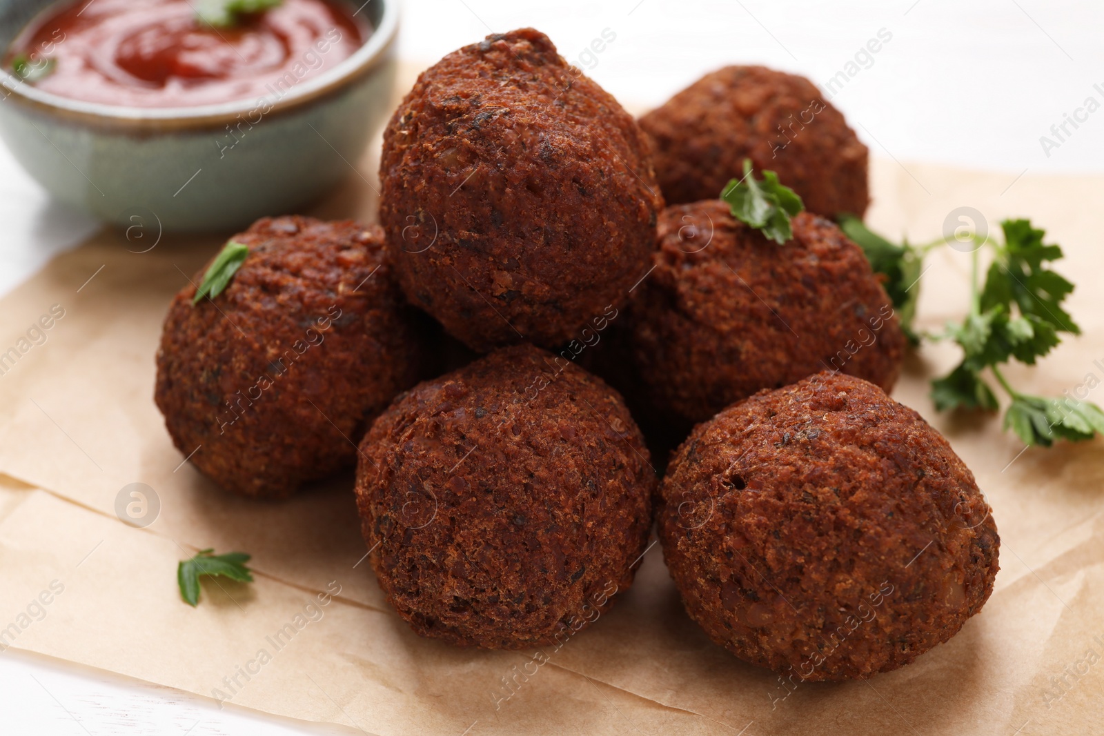 Photo of Delicious falafel balls and parsley on parchment paper, closeup. Vegan meat products