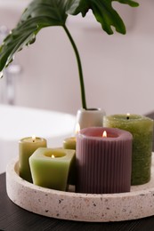 Photo of Different burning candles on tray in bathroom