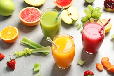 Photo of Three glasses of different juices and fresh ingredients on light background