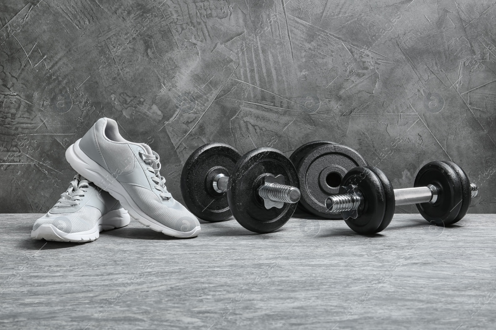 Photo of Composition with dumbbells and fitness accessories on floor. Space for text