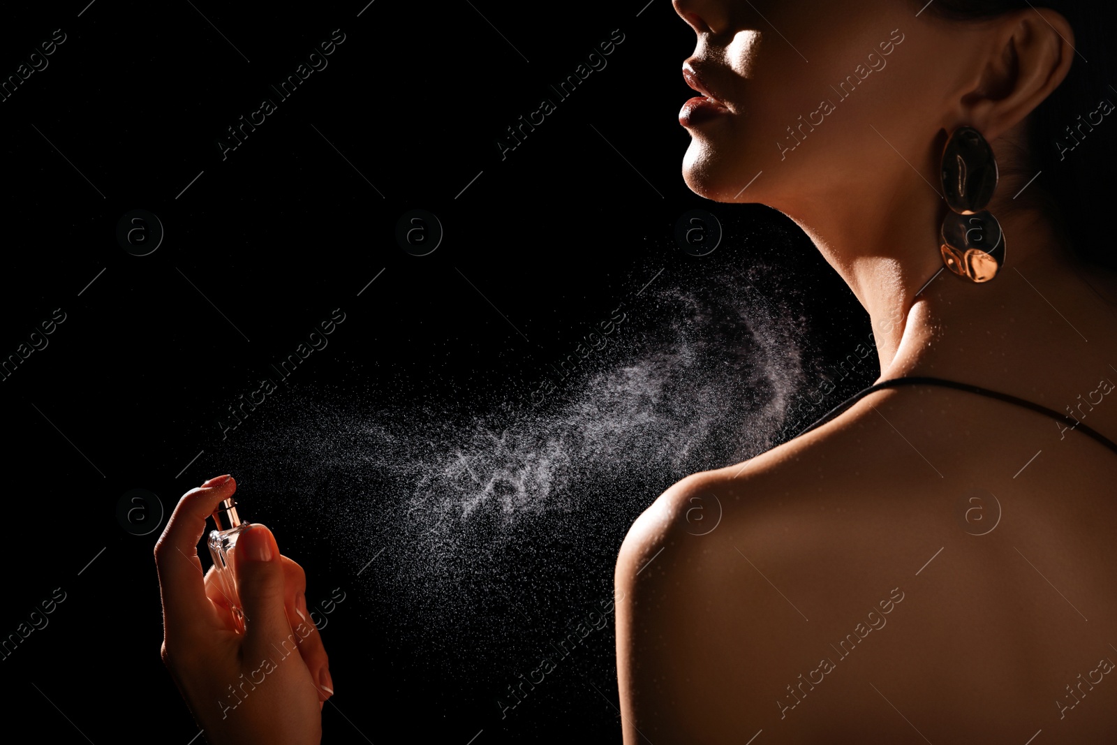 Photo of Woman spraying luxury perfume on black background, closeup