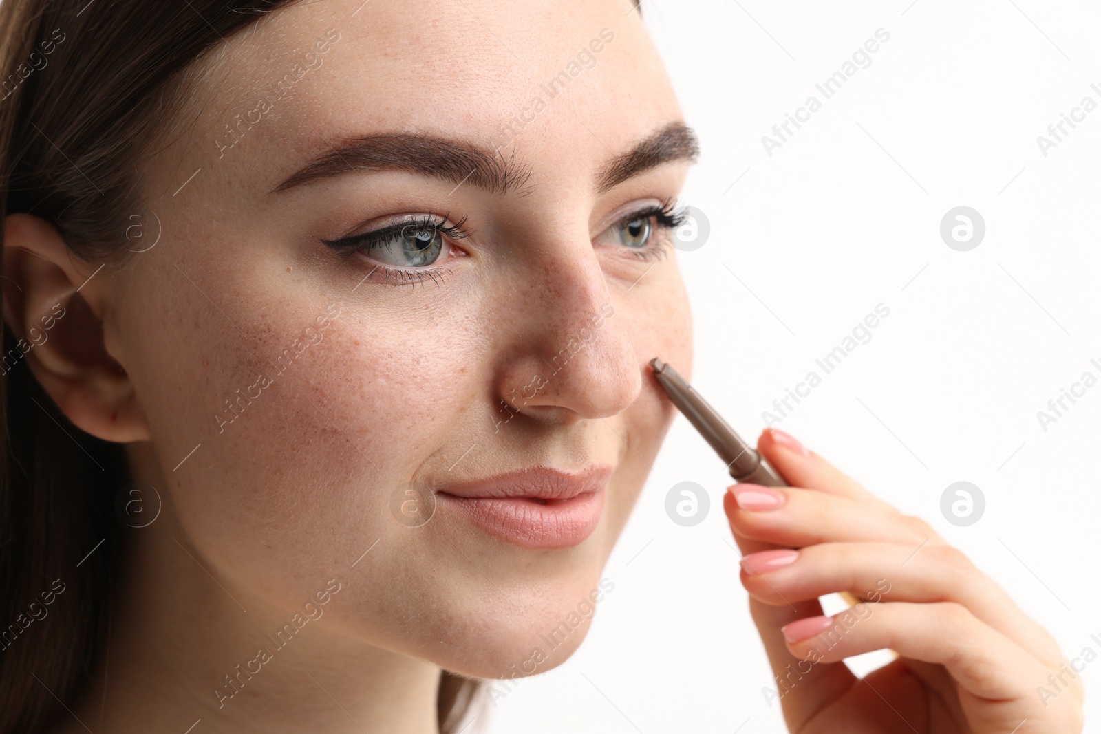 Photo of Beautiful woman drawing freckles with pen on white background, closeup