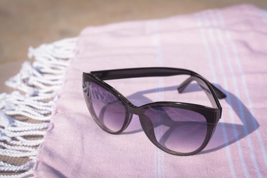 Stylish sunglasses on blanket outdoors, closeup. Beach accessories