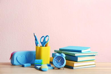 Different school stationery on wooden table against pink background