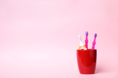 Baby toothbrushes in holder and space for text on color background