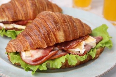 Photo of Tasty croissant with brie cheese, ham and bacon on plate, closeup