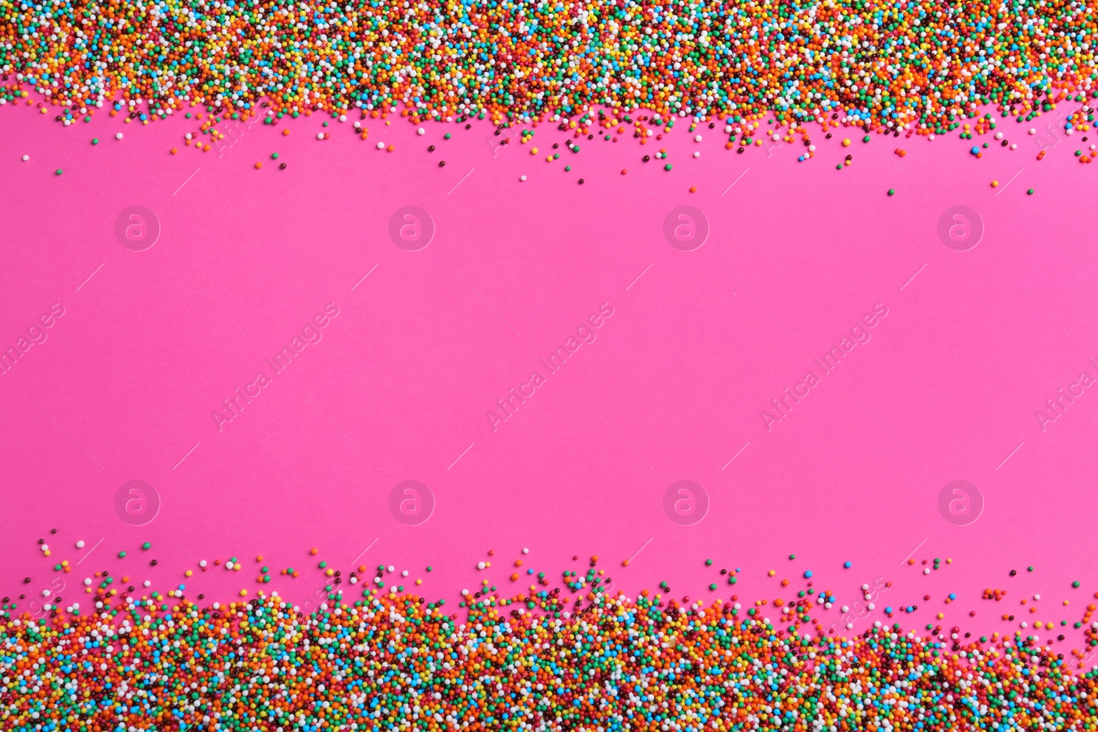 Photo of Bright colorful sprinkles on pink background, flat lay with space for text. Confectionery decor