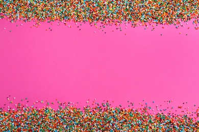 Photo of Bright colorful sprinkles on pink background, flat lay with space for text. Confectionery decor