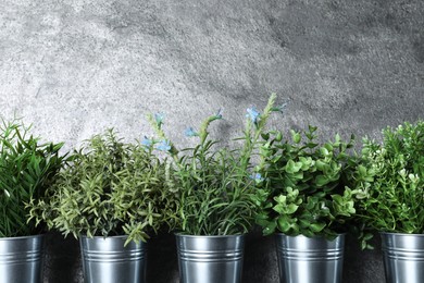 Photo of Different artificial potted herbs near grey wall