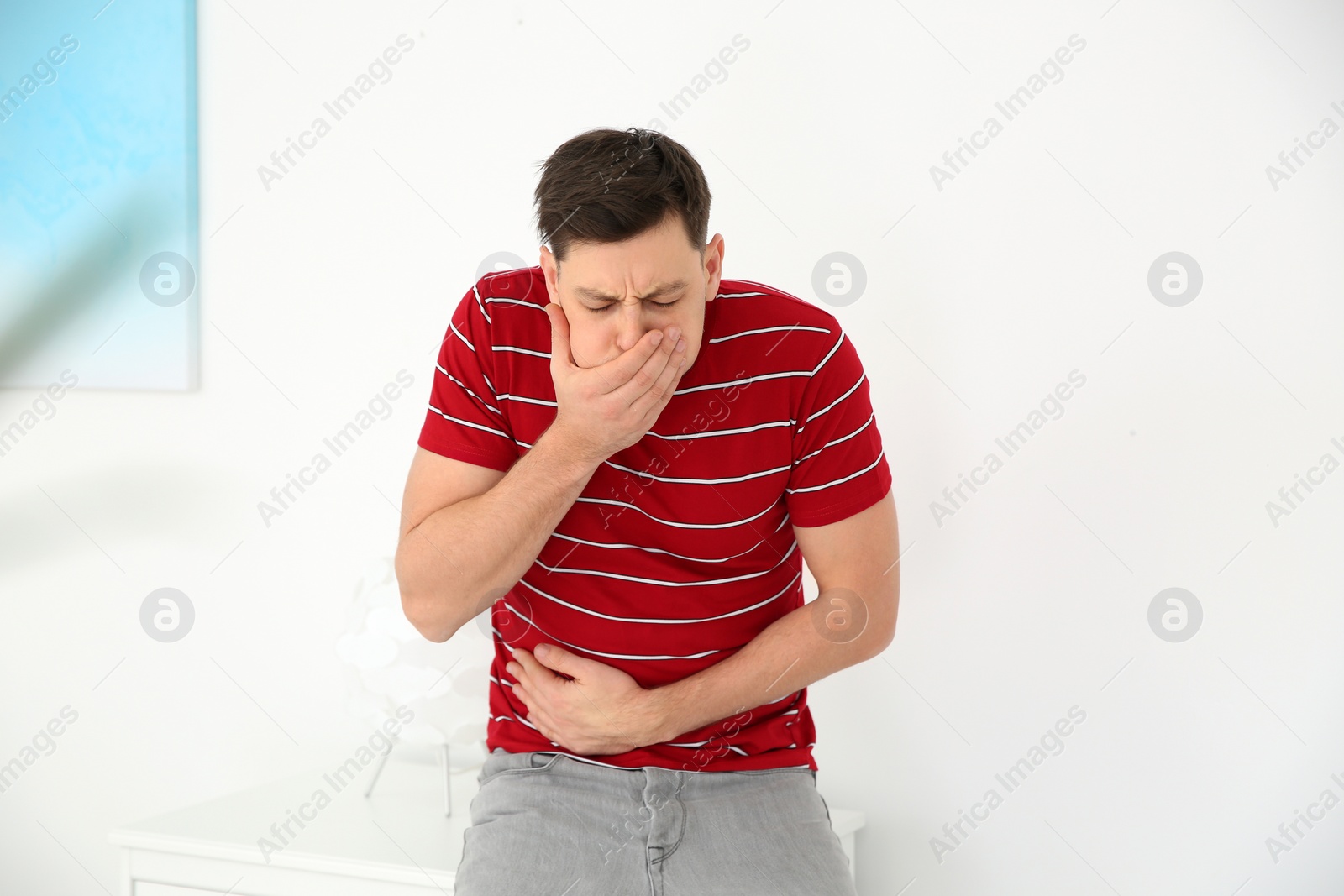 Photo of Young man having nausea at home. Feeling sick