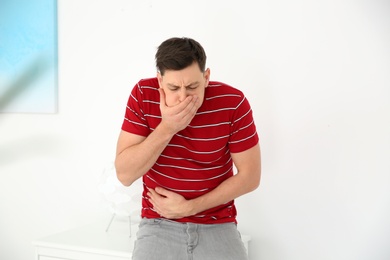 Photo of Young man having nausea at home. Feeling sick