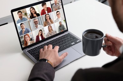 Image of Man with coffee participating in webinar via laptop at table, closeup