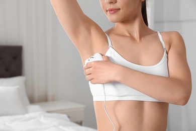 Photo of Woman doing armpit epilation procedure in bedroom, closeup. Space for text