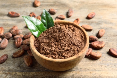 Photo of Bowl with cocoa powder on wooden table