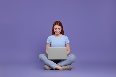 Photo of Smiling young woman working with laptop on lilac background