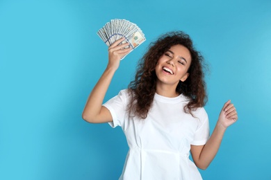 Young African-American woman with money on color background. Space for text