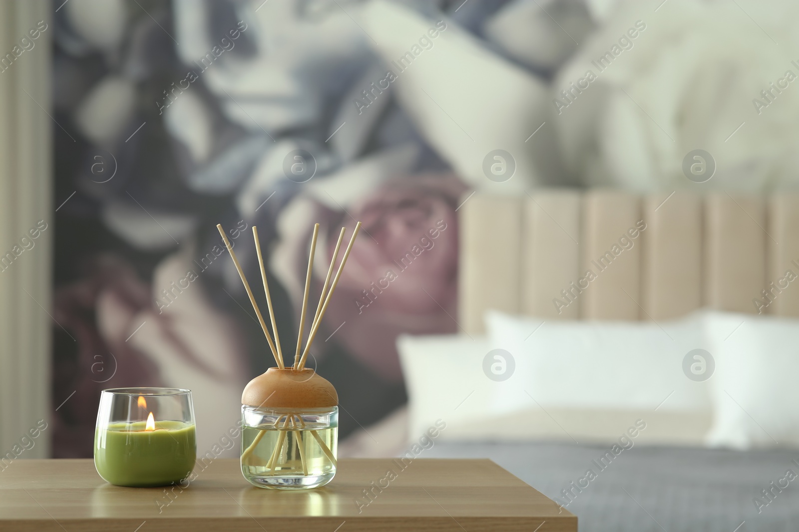 Photo of Aromatic reed air freshener and scented candle on table indoors. Space for text