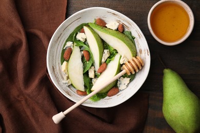 Delicious pear salad in bowl, honey and dipper on wooden table, flat lay