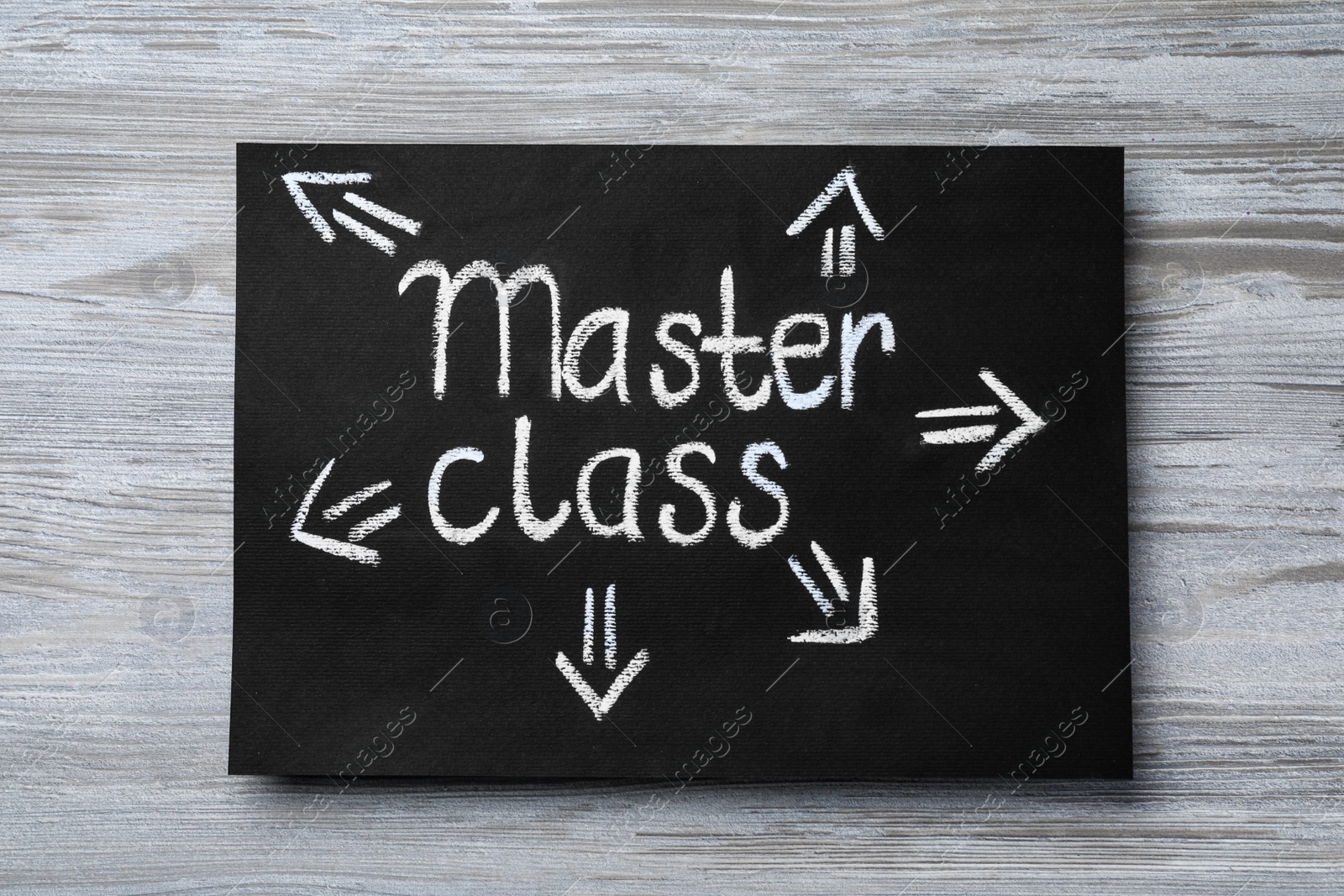 Photo of Blackboard with words Master Class and arrows on white wooden table, top view