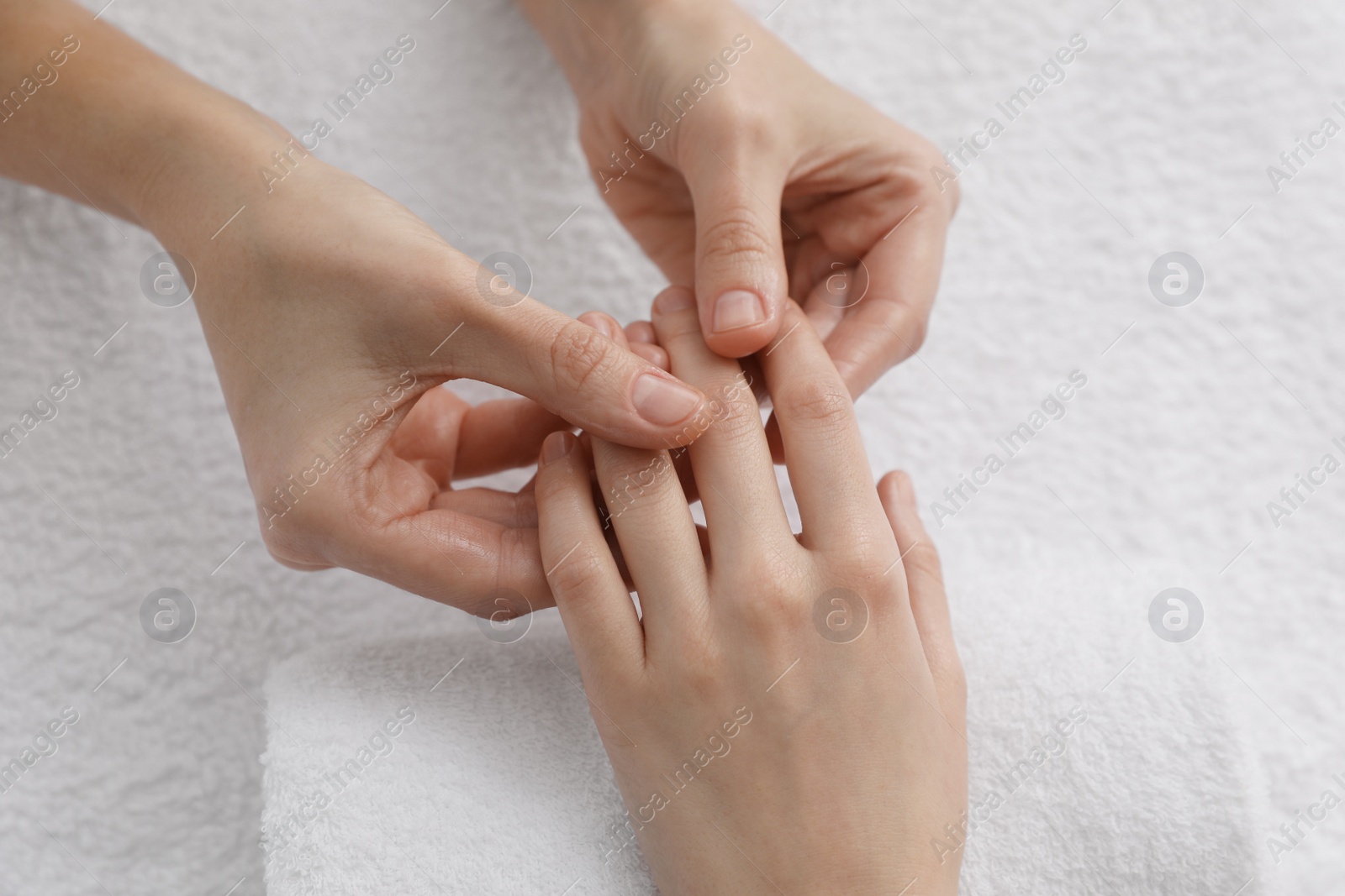 Photo of Woman receiving hand massage on soft towel, closeup