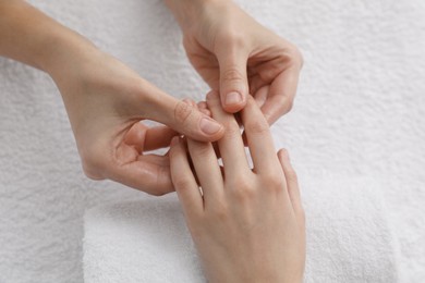 Photo of Woman receiving hand massage on soft towel, closeup