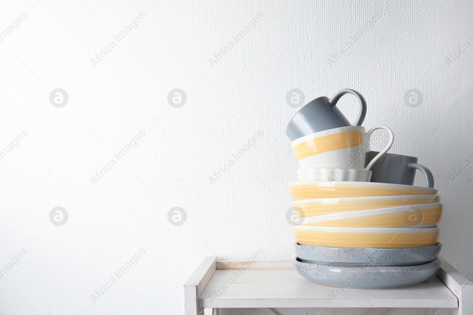Photo of Set of dinnerware on table against light background with space for text. Interior element