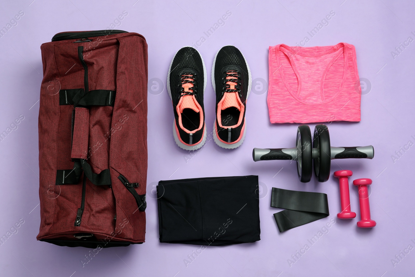 Photo of Gym bag and sports equipment on violet background, flat lay