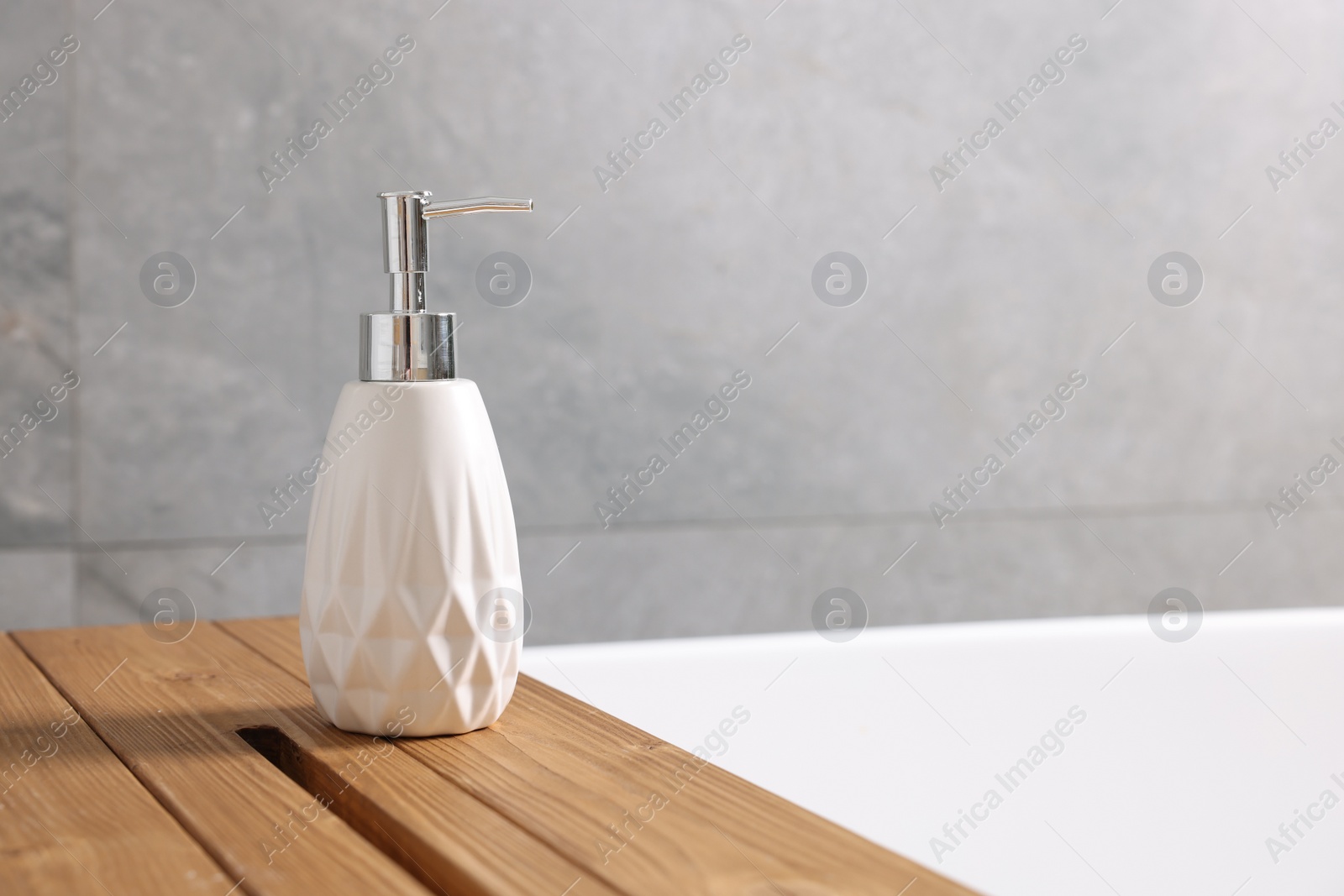 Photo of Bath accessory. Liquid soap dispenser on tub in bathroom, space for text