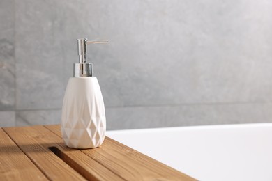 Photo of Bath accessory. Liquid soap dispenser on tub in bathroom, space for text