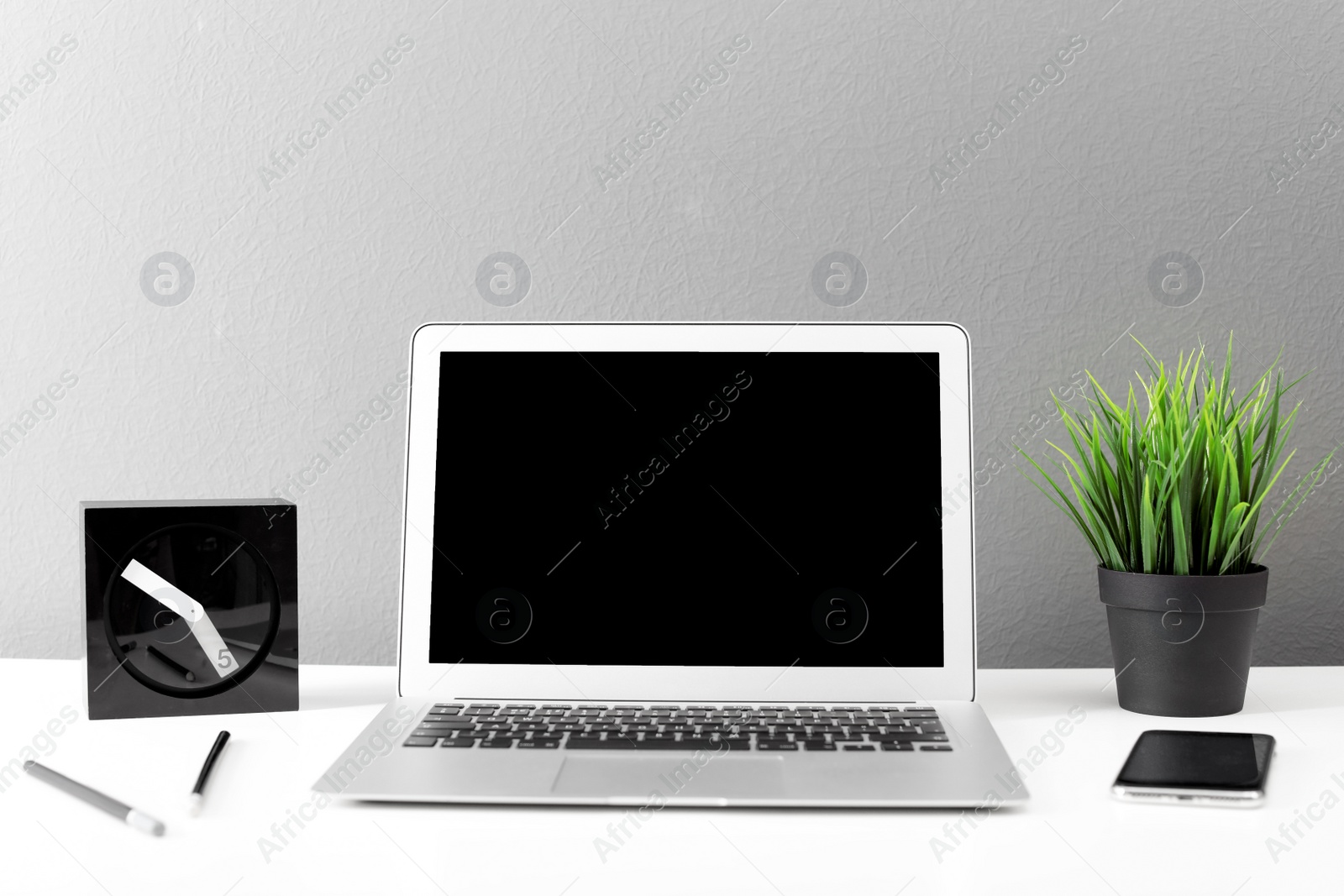 Photo of Modern laptop on table against gray wall. Mock up with space for text