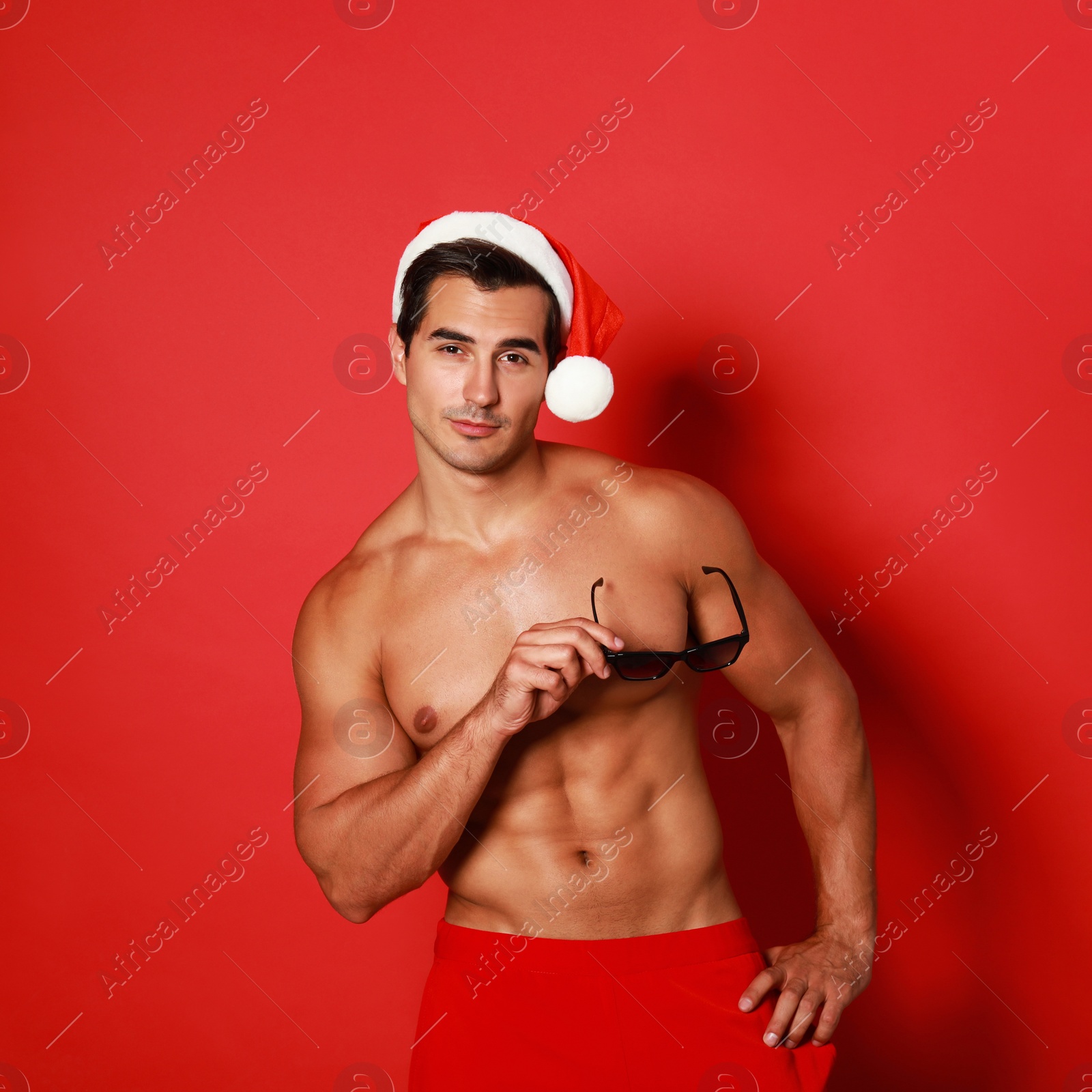 Photo of Sexy shirtless Santa Claus on red background