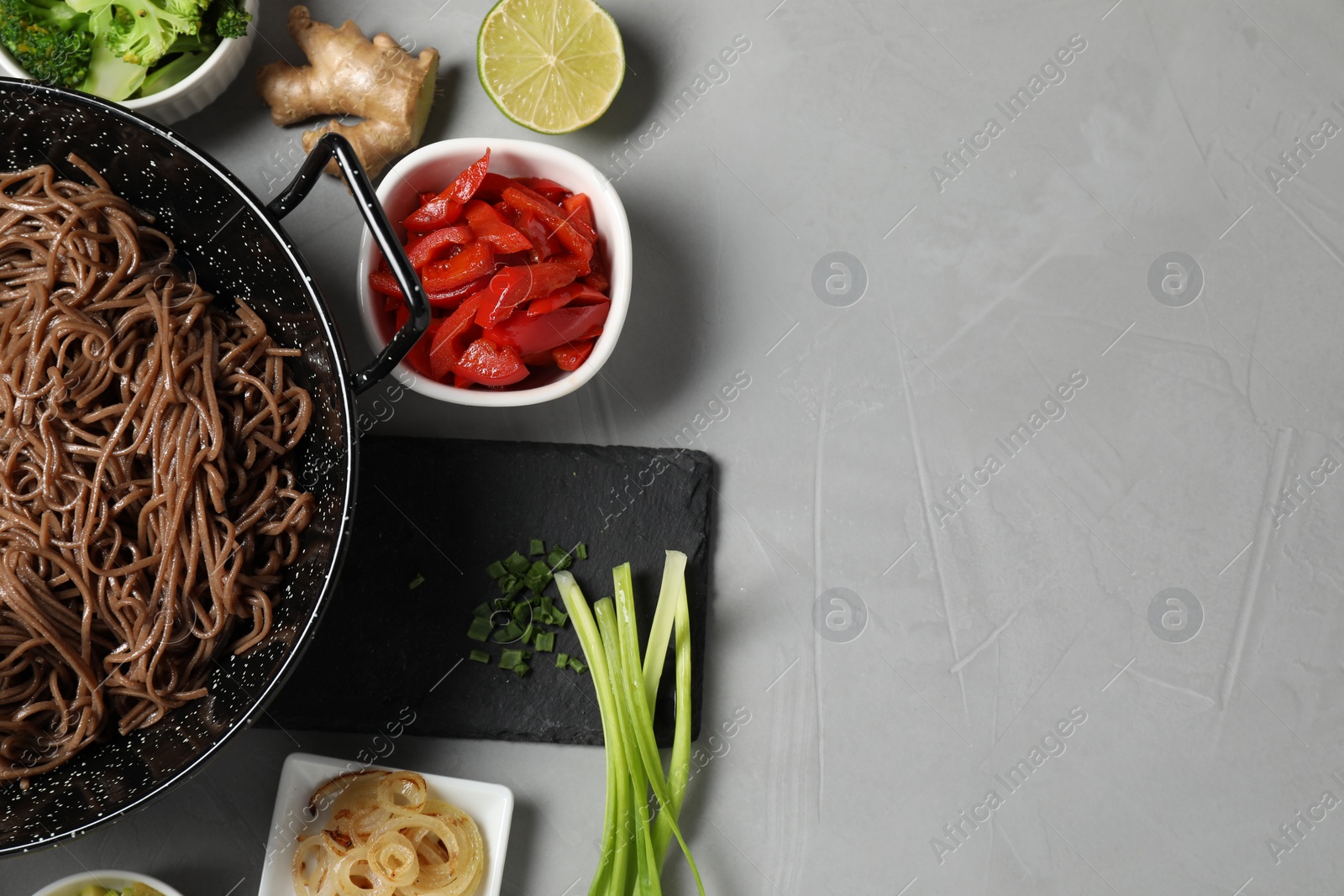 Photo of Wok with noodles and other products on light grey table, flat lay. Space for text