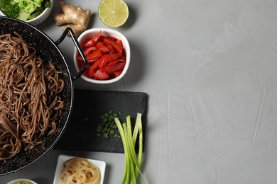 Photo of Wok with noodles and other products on light grey table, flat lay. Space for text