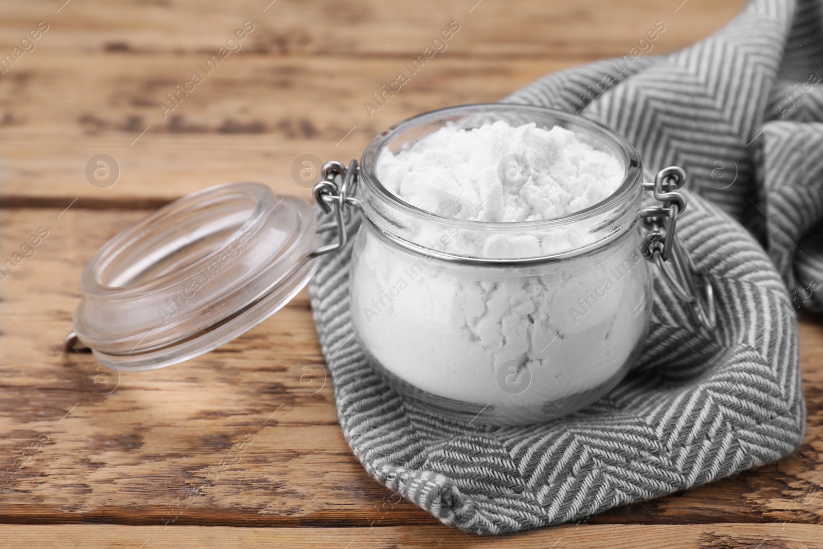 Photo of Glass jar of natural starch on wooden table, closeup