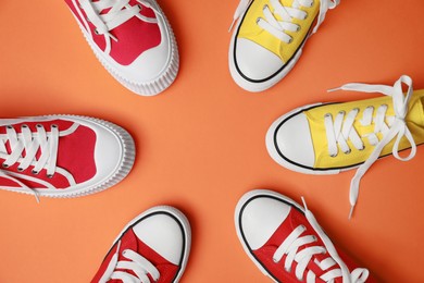 Photo of Different classic old school sneakers on orange background, flat lay
