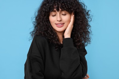 Photo of Happy young woman in stylish black sweater on light blue background