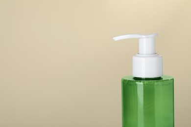 Photo of Bottle of cleansing gel on beige background, closeup with space for text. Cosmetic product