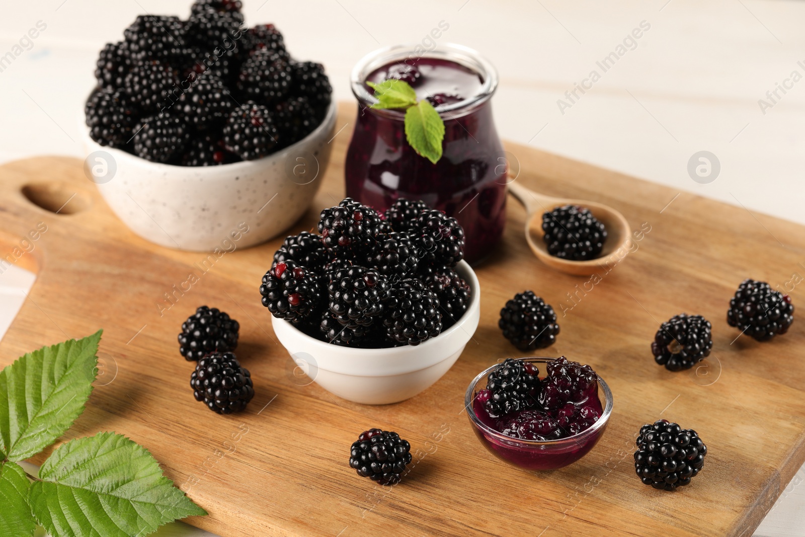 Photo of Tasty blackberry jam and fresh berries on table, closeup