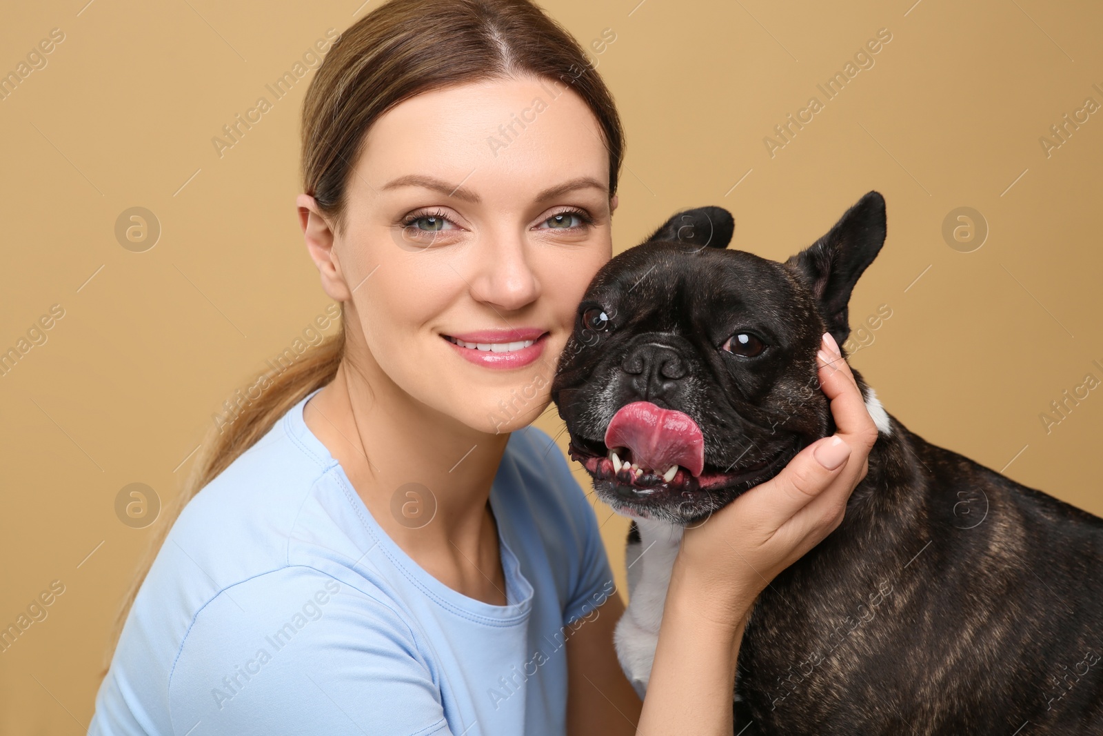 Photo of Portrait of happy woman with cute French Bulldog on beige background