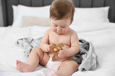 Photo of Cute baby boy with blanket and rattle sitting on bed at home