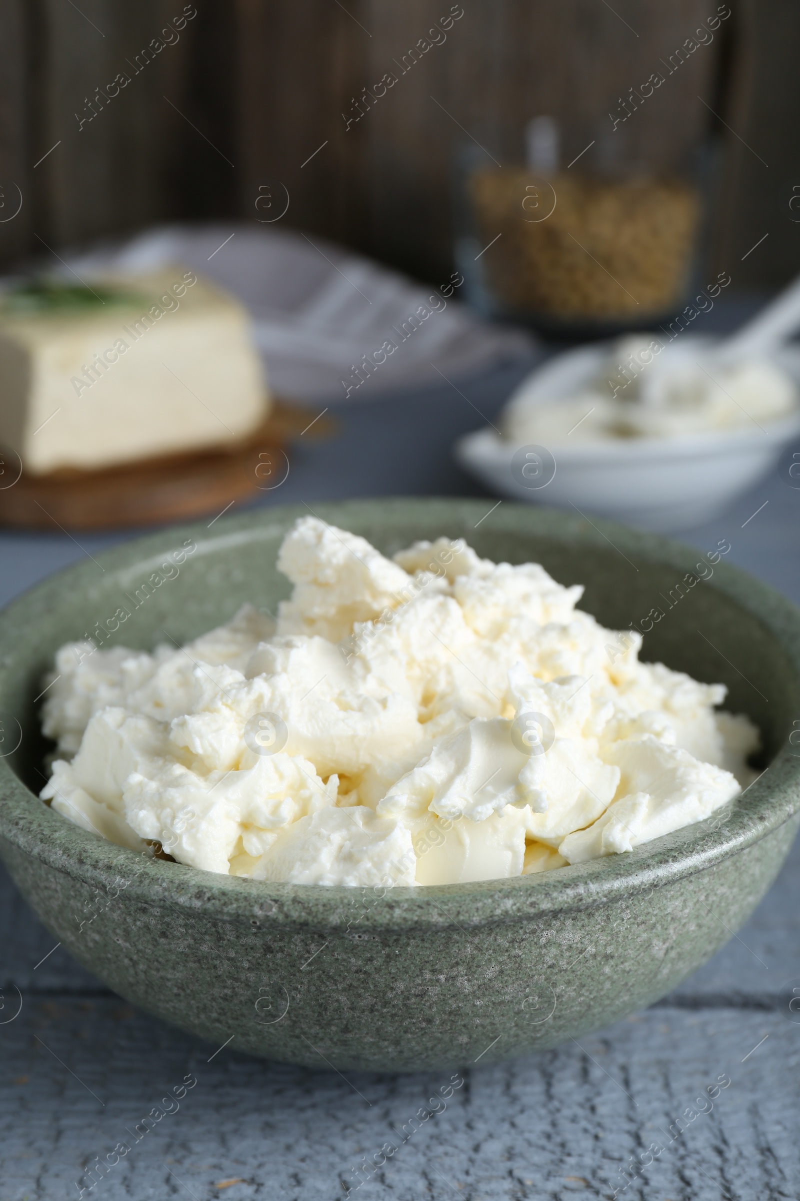 Photo of Delicious tofu cream cheese in bowl on grey wooden table