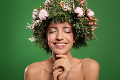 Happy young woman wearing wreath on green background