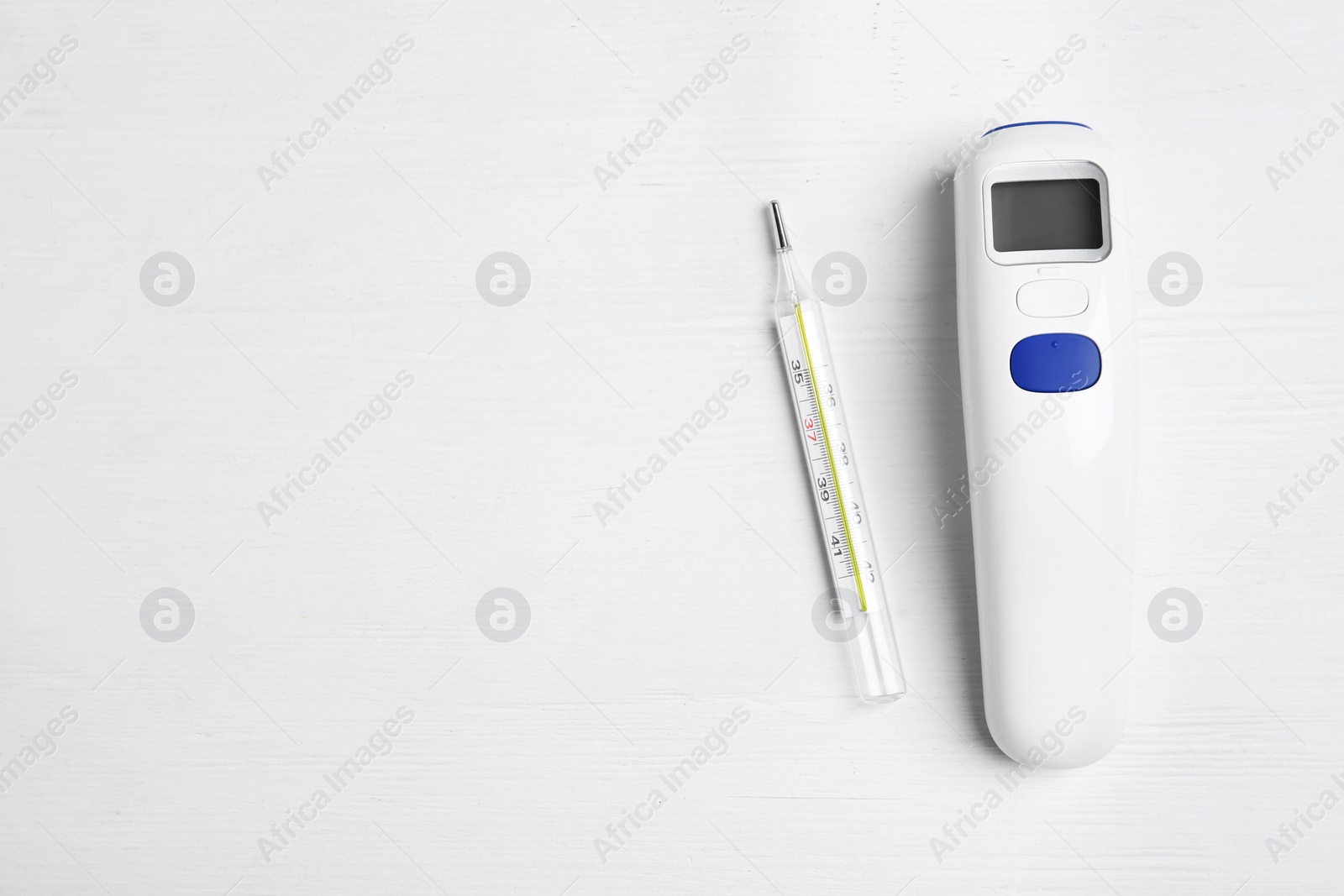 Photo of Non-contact infrared and mercury thermometers on white wooden background, flat lay. Space for text