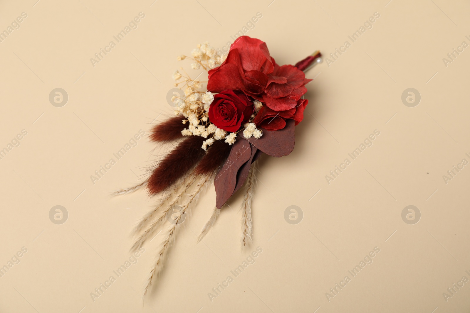 Photo of Stylish red boutonniere on beige background, top view