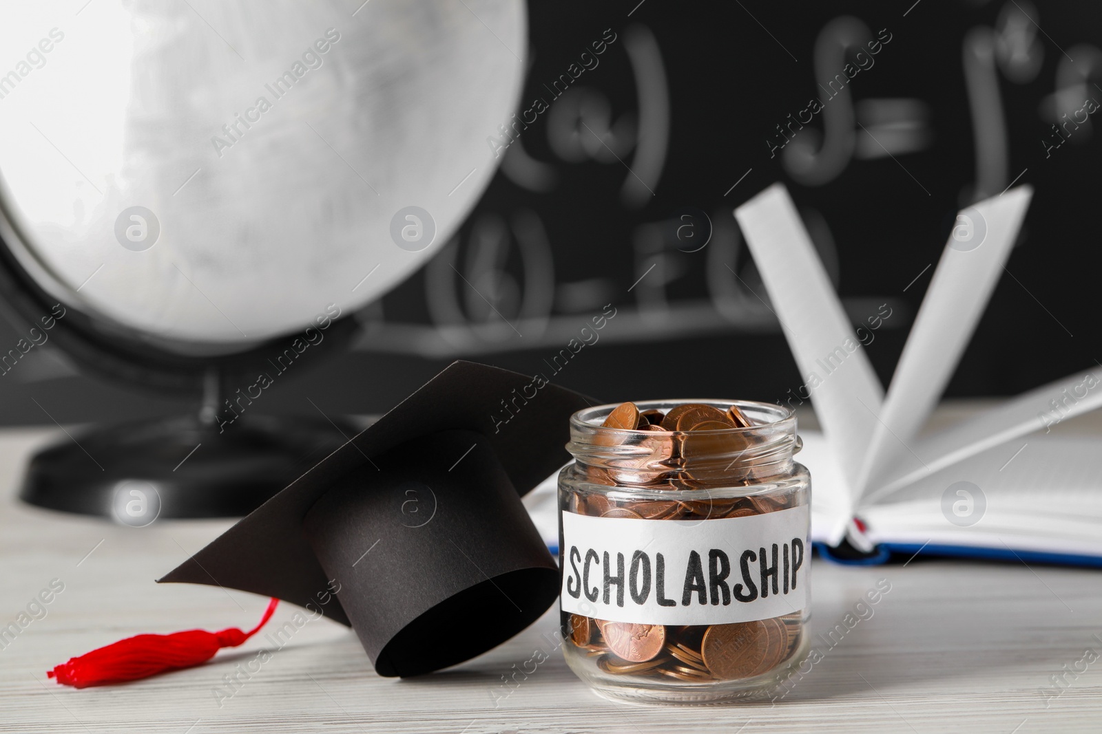 Photo of Scholarship concept. Glass jar with coins and graduation cap on white wooden table