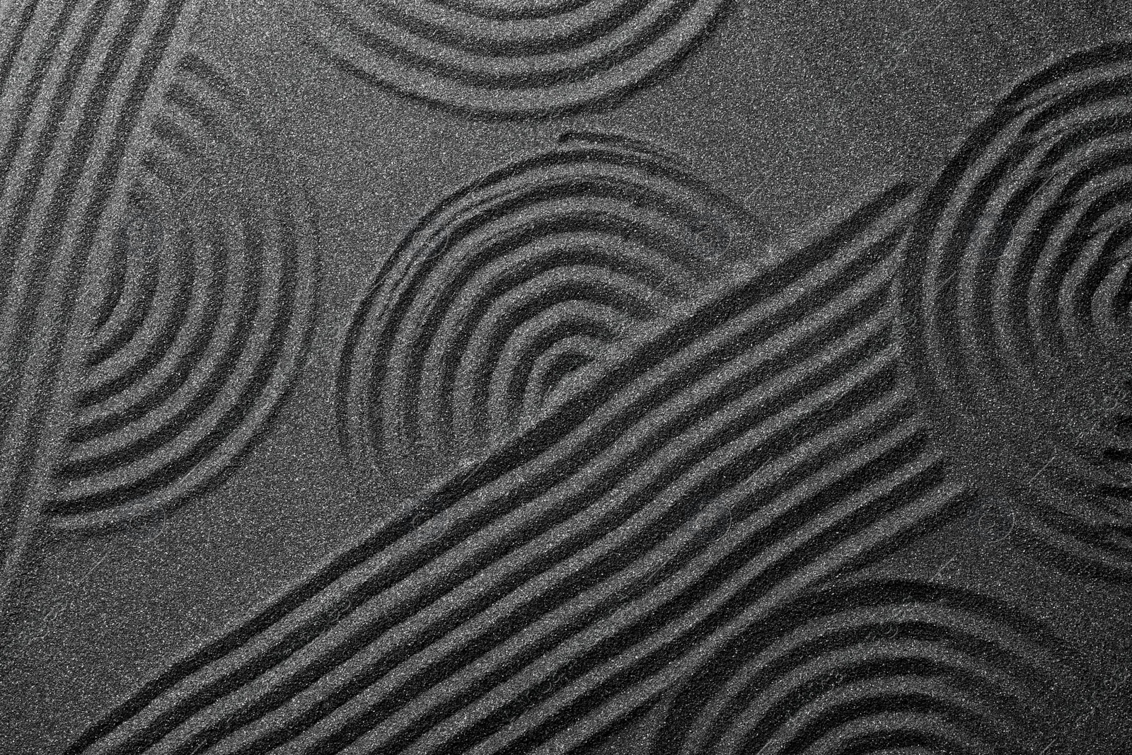 Photo of Pattern on decorative black sand, top view. Zen and harmony