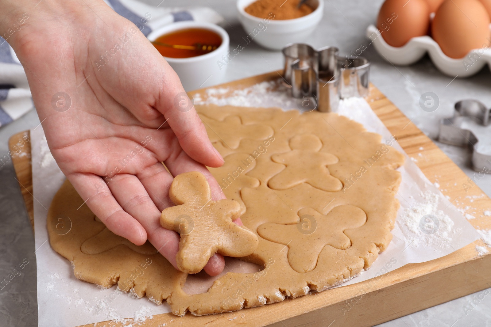 Photo of Making homemade Christmas cookies. Woman holding gingerbread man above table, closeup