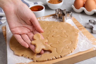 Making homemade Christmas cookies. Woman holding gingerbread man above table, closeup